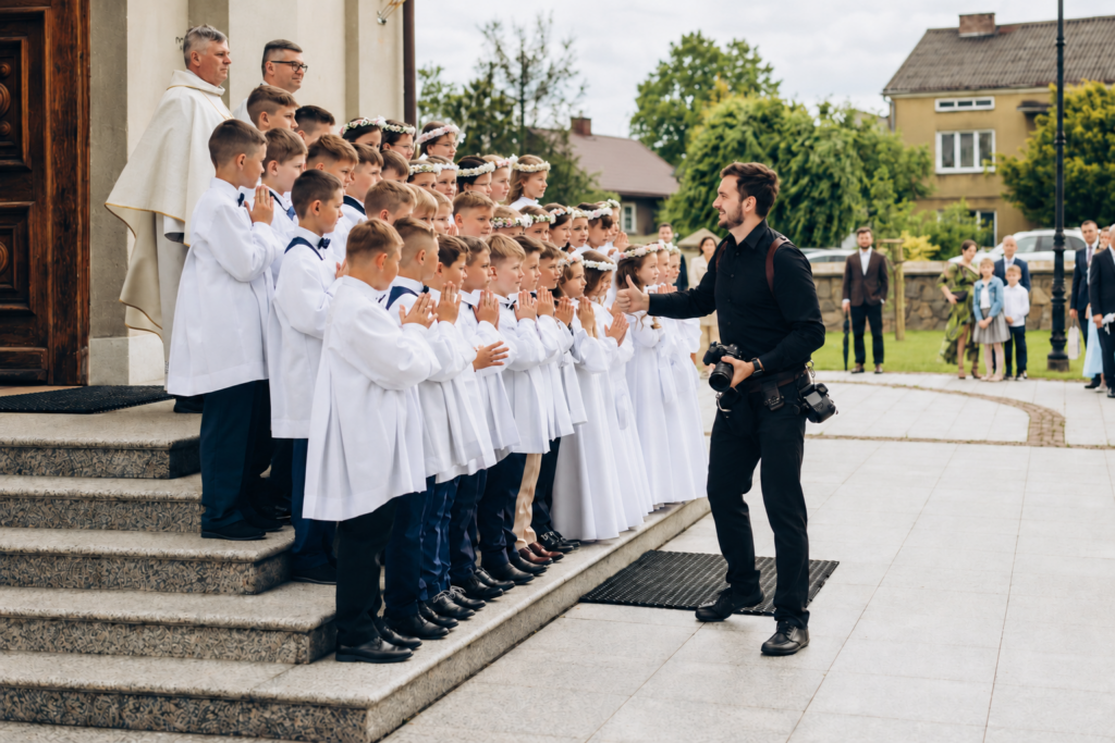 Fotograf ustawia dzieci do zdjęcia grupowego przed kościołem