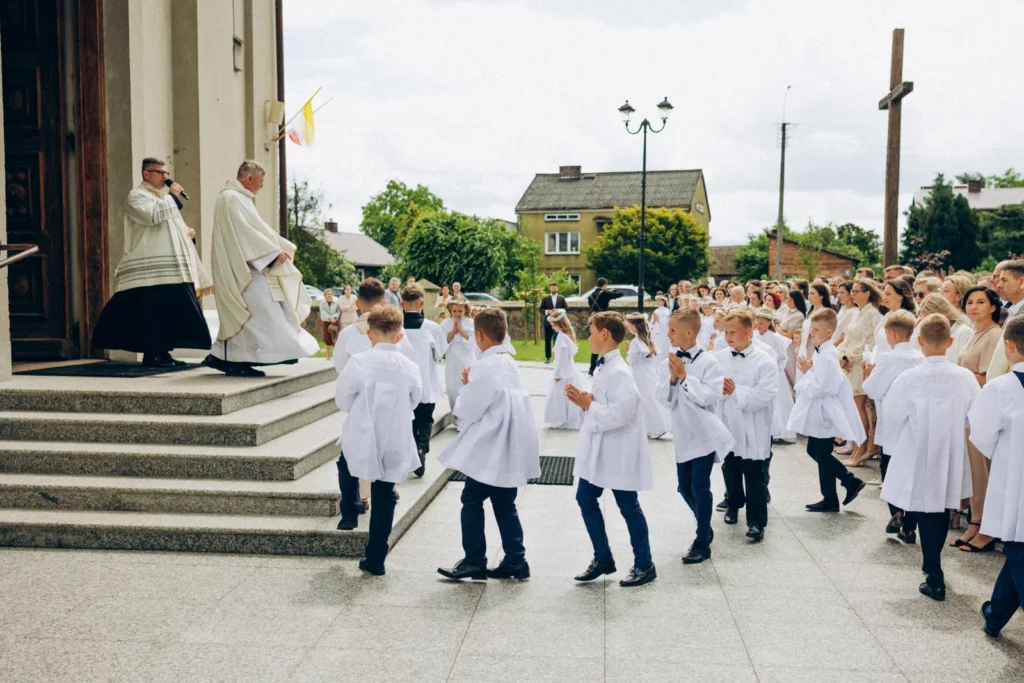 Dzieci w strojach komunijnych wchodzą do kościoła