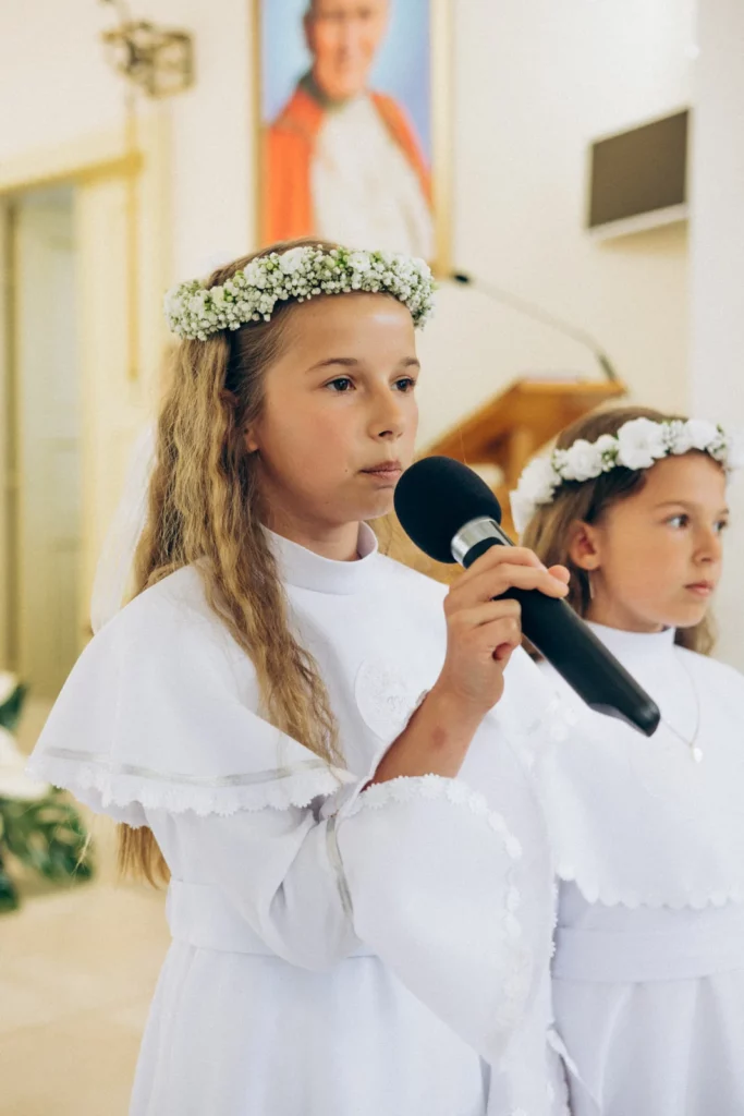 Dziewczynka w wianku czyta do mikrofonu w kościele