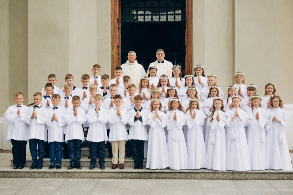 Cała grupa dzieci z księżmi przed wejściem do kościoła