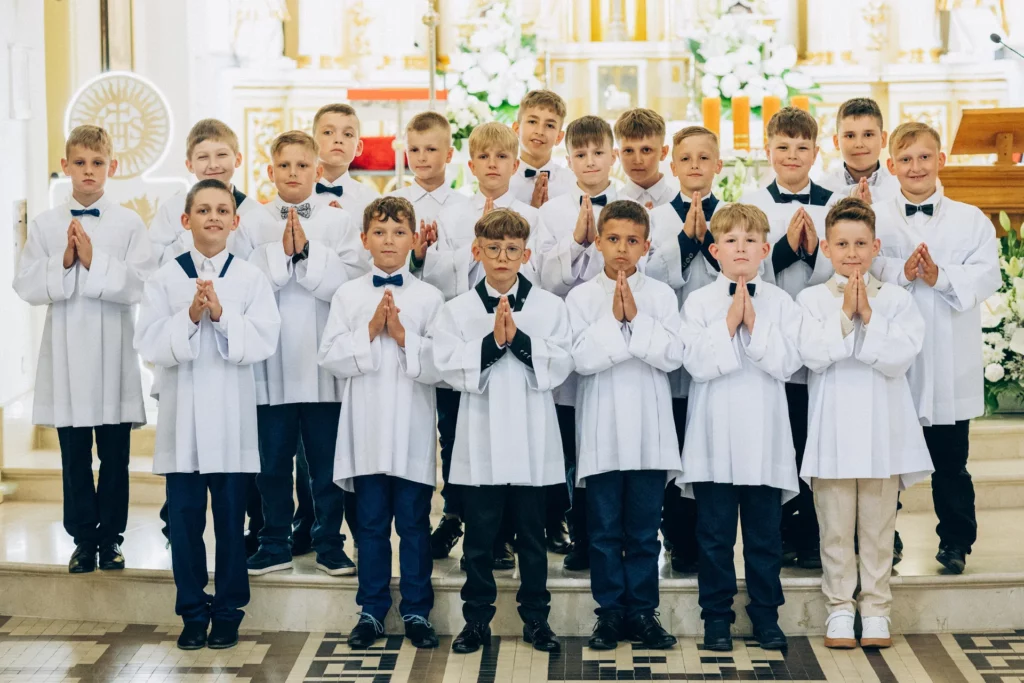 Chłopcy w strojach komunijnych pozują przed ołtarzem