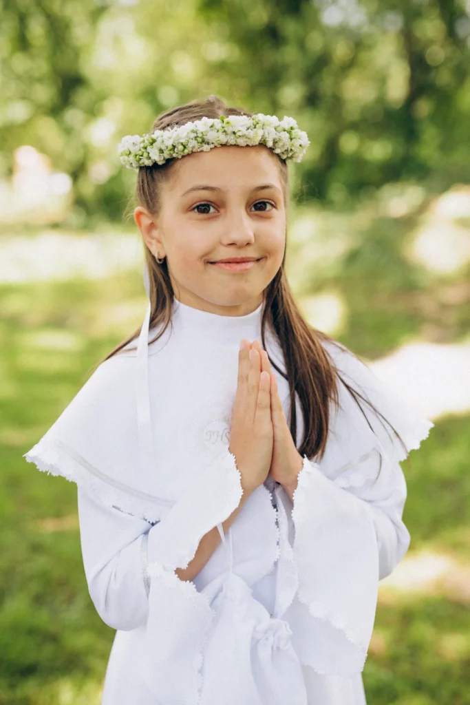 Uśmiechnięta dziewczynka w wianku ze złożonymi dłońmi