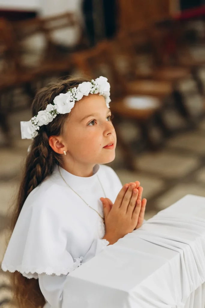 Dziewczynka ze złożonymi dłońmi przy ławce w kościele