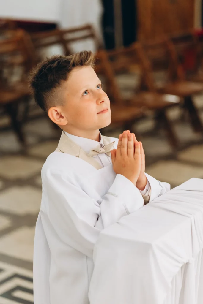 Portret chłopca w stroju komunijnym ze złożonymi dłońmi